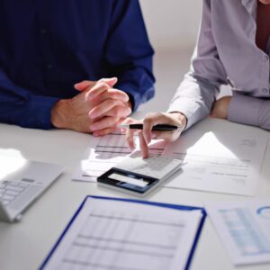 a man and woman sitting at a table looking at papers