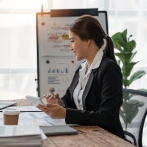 a woman sitting at a desk holding a pen and a book