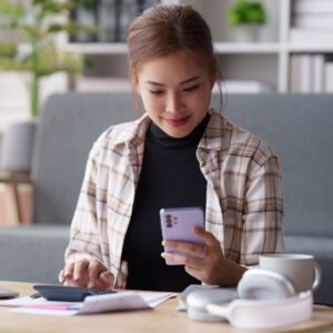 a woman sitting at a table looking at a phone