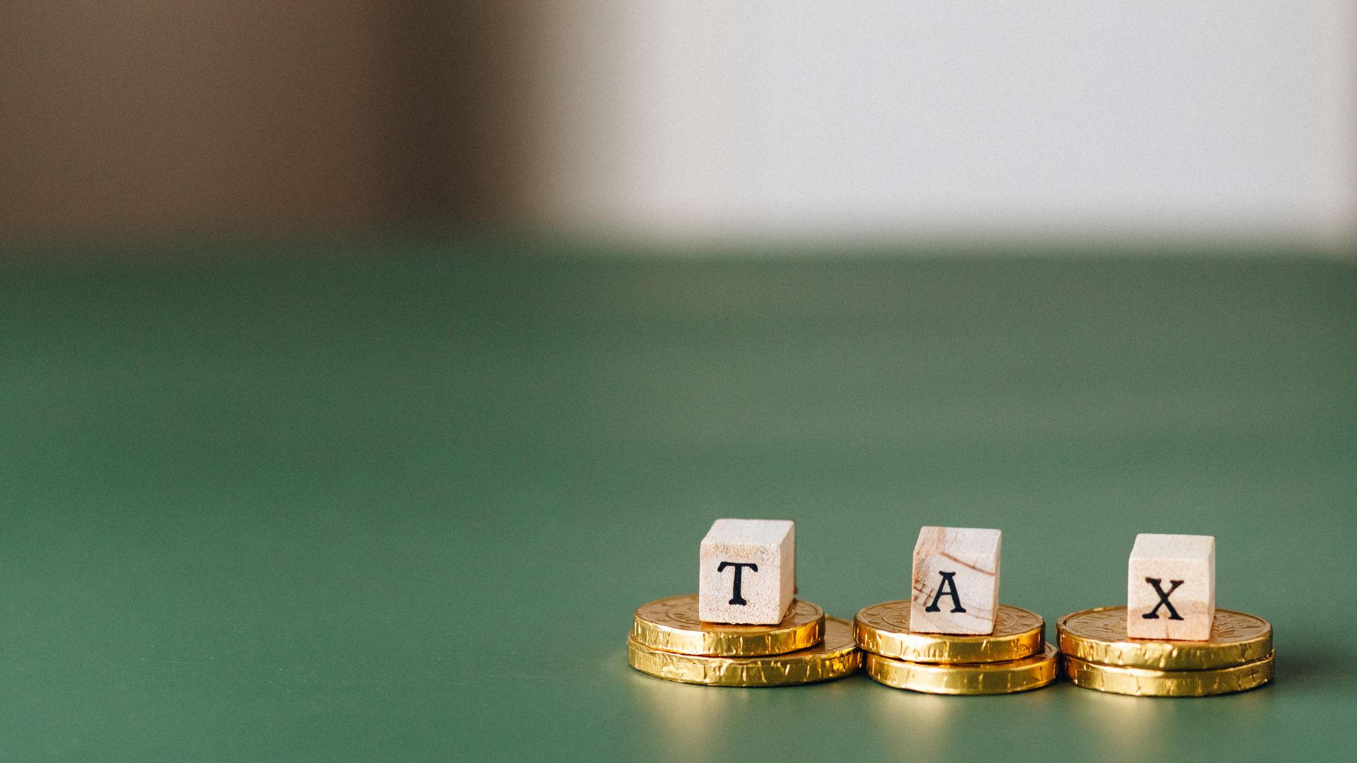 the word tax on letters stacked on some gold coins